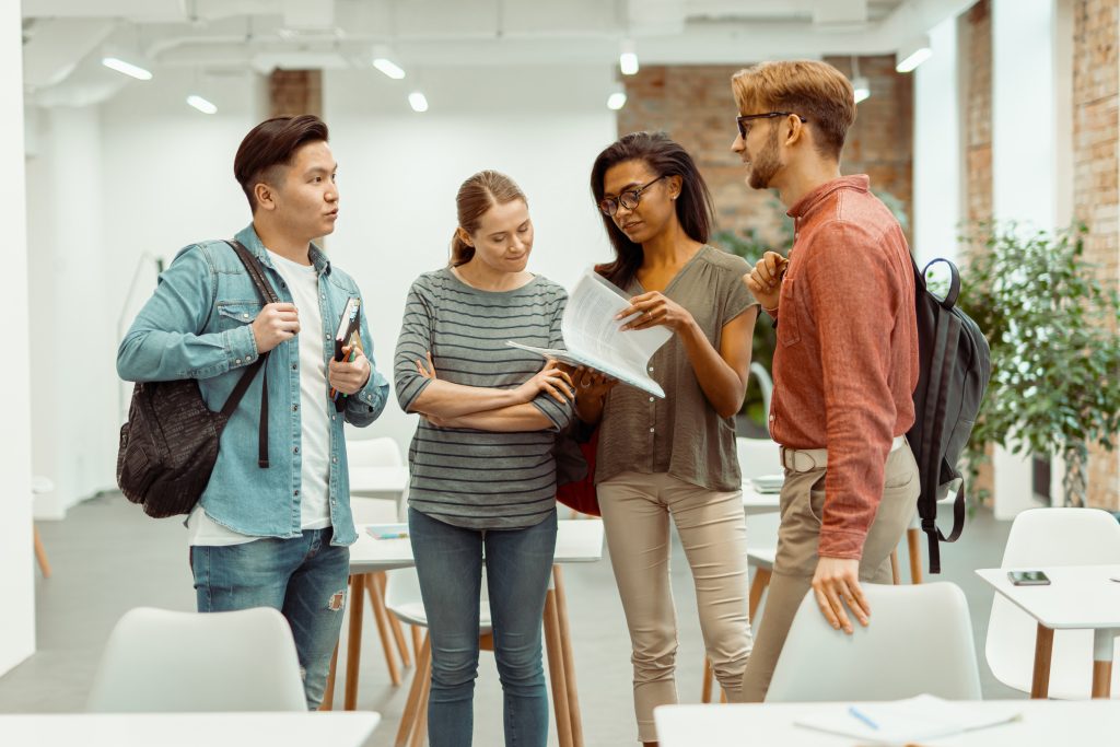 Four students standing and talking in classroom